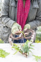 Woman placing fern fronds in the wire at the top of the heart