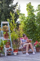 Girl relaxing on roof terrace with raised bed and container grown vegetables and herbs.