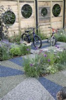 'On Your Bike!' at BBC Gardener's World Live 2021 - veoldrome made from rubber leading around a cycling themed garden with fence panels with bicycle tyre cut out shapes
