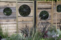 'On Your Bike!' at BBC Gardener's World Live 2021 - fence panels with bicycle wheels as cut out shapes in a cycling themed garden