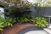 Curved composite timber bench seat in an innercity courtyard garden with steps leading to an upper level.