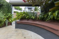 Inner city courtyard garden with inbuilt curved composite timber bench seating.