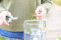 Woman placing grevillea sprigs in the large glass container