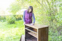 Woman sanding the wooden cabinet