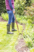 Woman using edging shears to trim the edge of the lawn
