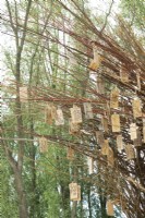 Arch of willow branches filled with wooden wish plates made by nature artist Will Beckers.