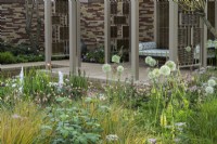 Herbaceous beds planted with  lupins,  white alliums, geums, astrantias, pimpinella, verbascums and ornamental grasses in front of pavillion made of willow screens - Stitchers Sanctuary Garden - Design: Frederic Whyte