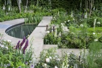 Semi-circular pond surrounded by stone  paving and green and white herbaceous planting - The Perennial Garden With Love