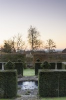 Yew hedges frame a pond in a formal town garden in winter