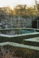 Beds framed by box hedges dusted with frost in a formal vegetable garden in winter