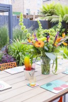 Decorative rainbow cactus next to bouquet on dining table with view to play area behind