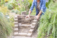 Woman creating a sloped wedge with the pavers