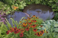 Helenium 'Moerheim Beauty' and marginal plants surrounding two staggered Torc Pots corten steel water bowls.  The Daily Mail and RHS Planet-Friendly Garden, RHS Hampton Court Palace Garden Festival 2022.  Designer: Mark Gregory 