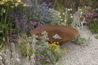 Water bowl feature with submerged rock surrounded by drought-tolerant herbaceous planting - Turfed Out Garden, RHS Hampton Court Palace Garden Festival 2022.  July.  Designer: Hamzah-Adam Desai  