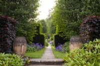 Terracotta urns beside a path through Yew hedge to the rose garden at Newby Hall Gardens.