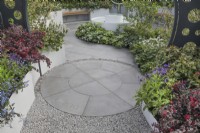 Circular paving bordered by planting in the CRUK Legacy Garden at RHS Malvern Spring Festival 2022