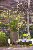 Easter moss nest with eggs and decorative moss container with heart and bouquet of Helleborus, Cornelian cherry twigs and Vaccinium myrtillus - blueberry.