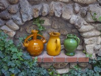 Pottery wine jugs decorate alcove in stone garden wall