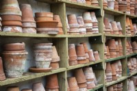 Old terracotta pots stacked on wooden shelves