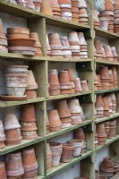Old terracotta pots stacked on wooden shelves