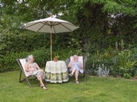 Two women relaxing on deckchairs in garden
