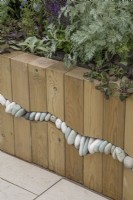 Raised wooden edged bed with pebble detail in the Metamorphosis garden at BBC Gardener's World Live 2022
