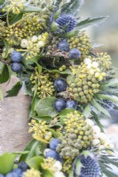 Ivy, Symphoricarpos and Eryngium wreath on wooden table