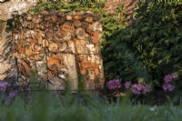 The bug hotel, created out of logs, terra cotta bricks and pots, fir cones, hay, bamboo canes and stones, is against the wall in the orchard at West Dean Gardens.