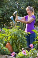 Woman placing sprinkler tops from watering can on the top of cane support for decoration and eye protection.
