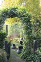 Overgrown arch and gate to garden.
