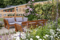 Seating area set amongst colourful planting and storage wall behind - Knolling with Daisies, RHS Hampton Court Palace Garden Festival 2022