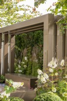 Metal pergola with box seating surroundedby grasses and Hydrangea quercifolia - Macmillan Legacy Garden: Gift the Future, RHS Hampton Court Palace Garden Festival 2022