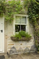 A row of wire cloches below a window box at Cow Close Cottage, North Yorkshire, in July