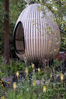 Bent oak swinging hide, suspended over naturalistic style planting with Kniphofia, Sanguisorba, Salvia and grasses - The Yeo Valley Organic Garden, RHS Chelsea Flower Show 2021
