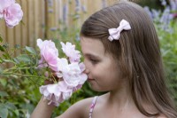 Young girl smelling roses in back garden