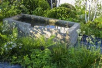 Old stone water trough in The Connections garden at RHS Hampton Court Palace Garden Festival 2022 