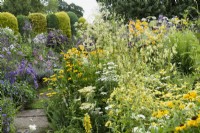 Colour themed borders in a cottage garden in July.