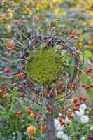 Outdoor decoration with rose hip wreath on a wood post.