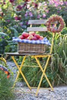 Woven basket with apples and wreath made from walnuts, spindle and common juniper.
