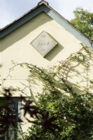 Gable end of cottage with plaque bearing a commemorative inscription.