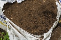 Opened bag of peat moss in backyard garden in summer