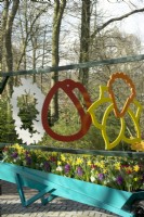 Decorative hanging flower mobiles: Hyacinth purple bright pink, Daffodils and red Tulips in blue wheelbarrow container at Keukenhof.