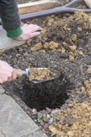 Woman digging 50 cm deep holes for the wooden posts