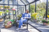 Woman sitting in greenhouse with a cup of tea