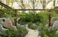 Concrete panels and a metal grid frame a pathway through perennials in the Samaritans' Listening Garden, a Show Garden designed by Darren Hawkes at the RHS Chelsea Flower Show 2023
