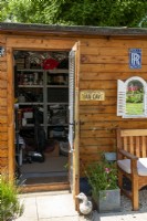 Garden shed with open door, showing metal shelving and storage of contents - Open Gardens Day, Old Newton, Suffolk