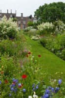 Grass path through deep herbaceous borders in 16th century garden of classical design - Helmingham Hall, Suffolk 