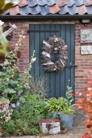 Containers at entrance door decorated with rustic wreath.