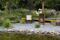 A waterside terrace is built in reclaimed granite setts, and edged in a reclaimed timber boardwalk edged in a border of leafy shrubs and perennials.