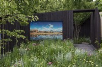 A prairie style area is overlooked by a large LED screen which, set into black-painted timber fencing, shows a natural American landscape.